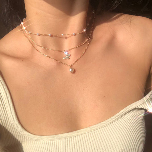 Crafted with multilayer gold-plated chains and detailed with pearl butterflies and a sun star pendant, this necklace makes a charming and timeless gift.